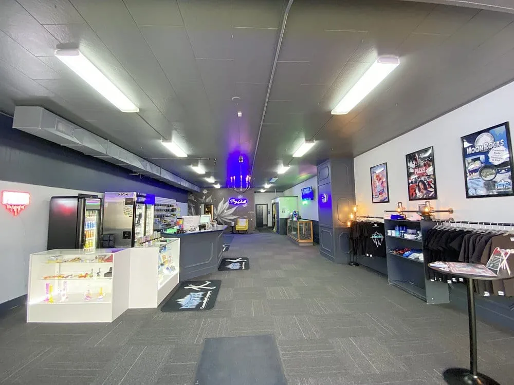 Wide view of a modern shop interior with a long checkout counter on the left, display cases, and clothing racks along the right side.